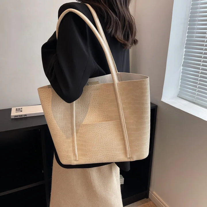 A woman carrying an elegant shoulder bag with a rich finish over one shoulder