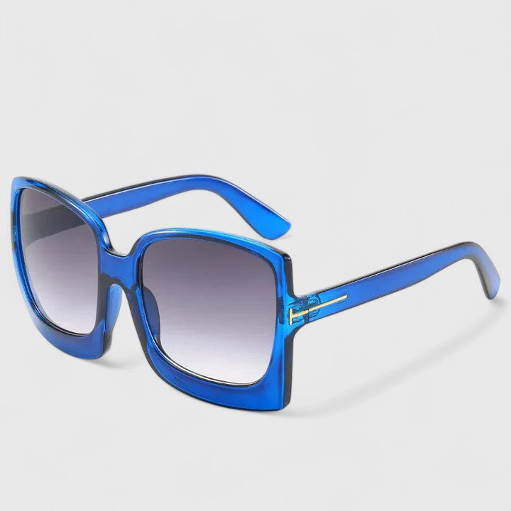 A woman on a sunny day wearing oversized gradient sunglasses, poised and glamorous.
