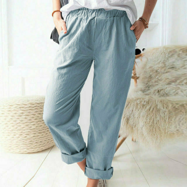 A woman standing relaxed in soft straight-leg trousers with a clean, elegant everyday look.