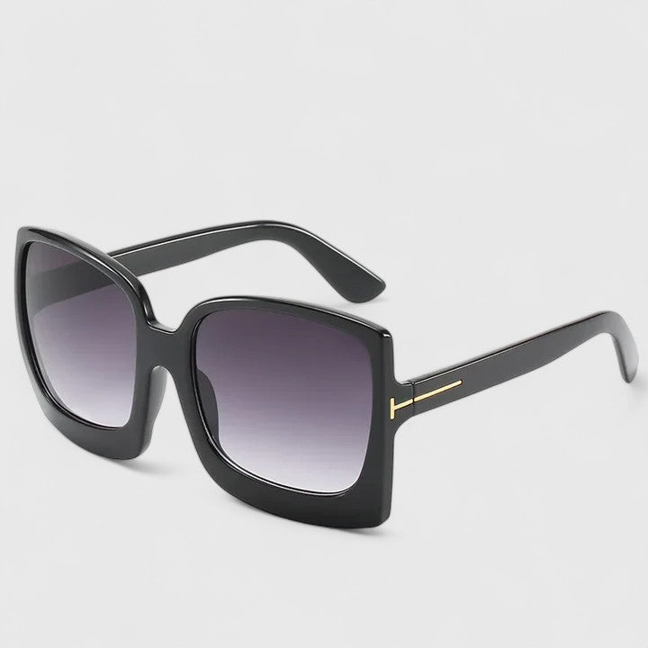 A woman on a sunny day wearing oversized gradient sunglasses, poised and glamorous.