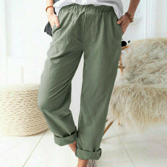 A woman standing relaxed in soft straight-leg trousers with a clean, elegant everyday look.