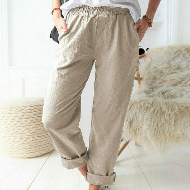 A woman standing relaxed in soft straight-leg trousers with a clean, elegant everyday look.