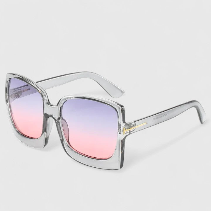 A woman on a sunny day wearing oversized gradient sunglasses, poised and glamorous.