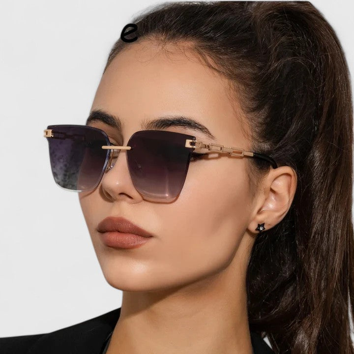 A woman wearing bold square sunglasses with brown gradient lenses and gold-tone chain-link arms.