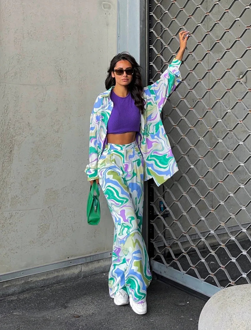 A woman wearing a bold abstract swirl-print shirt and matching wide-leg trousers in the city