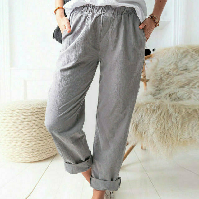 A woman standing relaxed in soft straight-leg trousers with a clean, elegant everyday look.