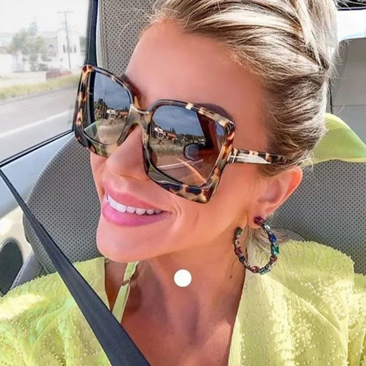 A woman on a sunny day wearing oversized gradient sunglasses, poised and glamorous.