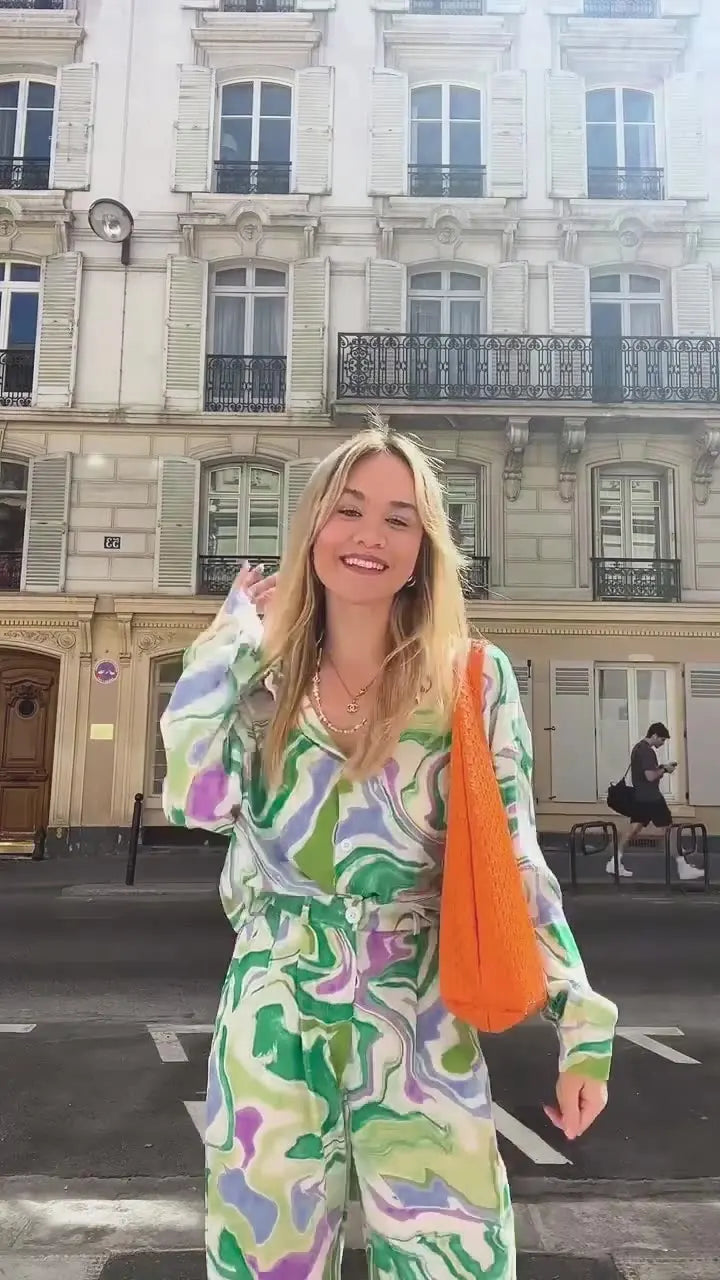 A woman wearing a bold abstract swirl-print shirt and matching wide-leg trousers in the city