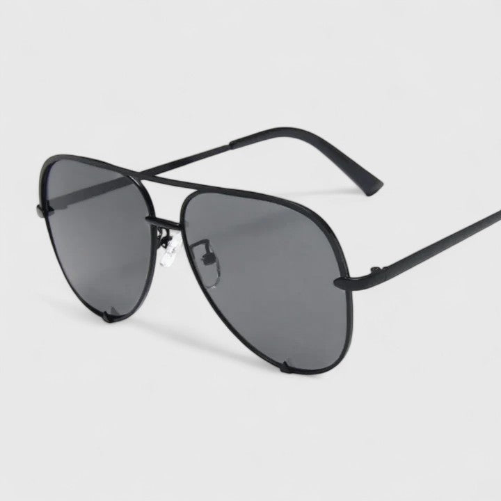 A woman by the sea wearing aviator sunglasses with gradient mirror lenses, relaxed in the sun.