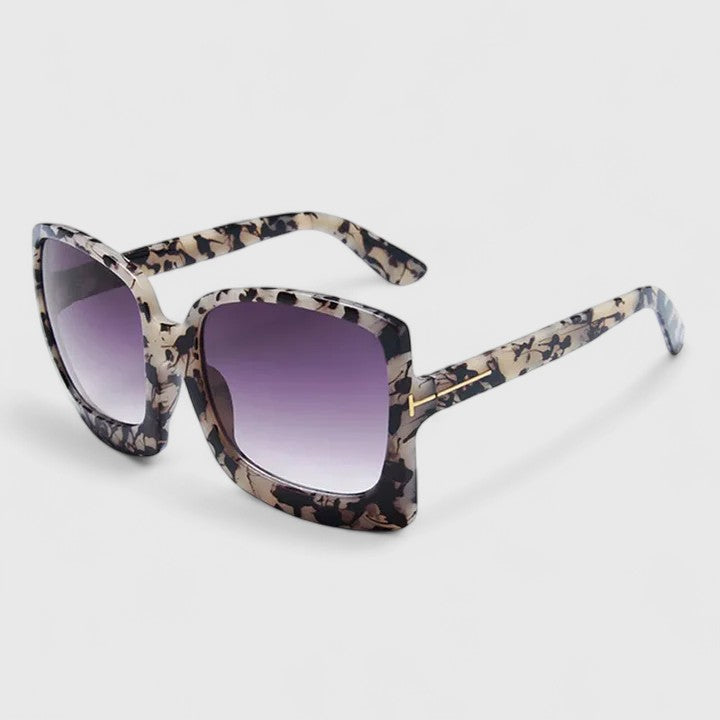 A woman on a sunny day wearing oversized gradient sunglasses, poised and glamorous.