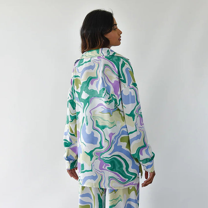 A woman wearing a bold abstract swirl-print shirt and matching wide-leg trousers in the city
