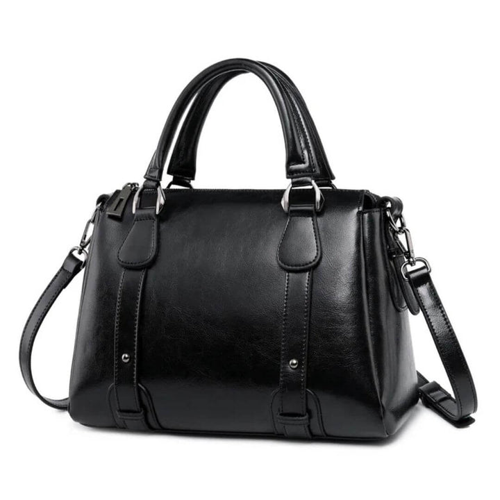 A woman with a polished structured shoulder bag resting at her hip while out for the day.
