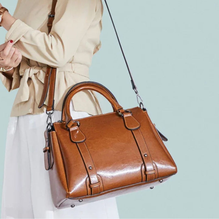 A woman with a polished structured shoulder bag resting at her hip while out for the day.