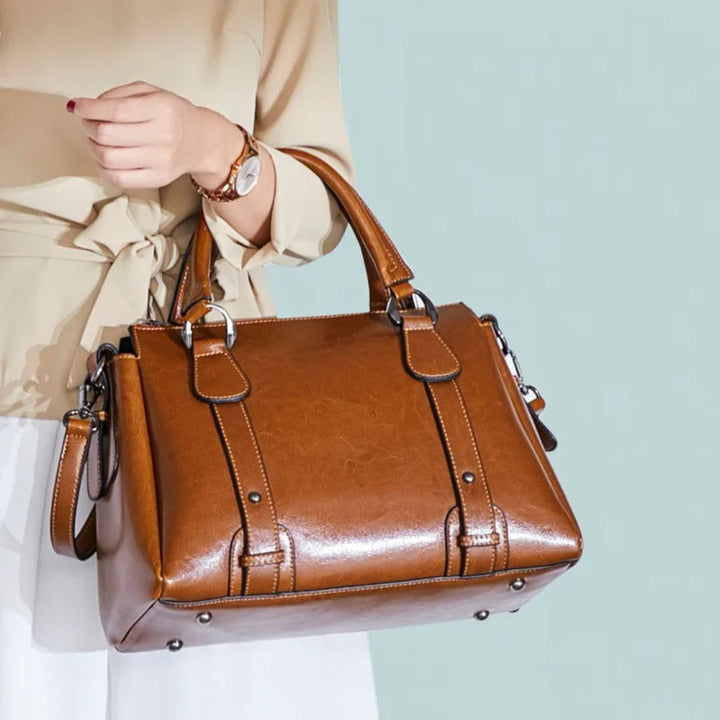 A woman with a polished structured shoulder bag resting at her hip while out for the day.