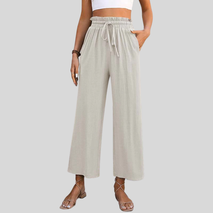 A woman in light cropped wide-leg trousers styled with sandals for a relaxed summer look.