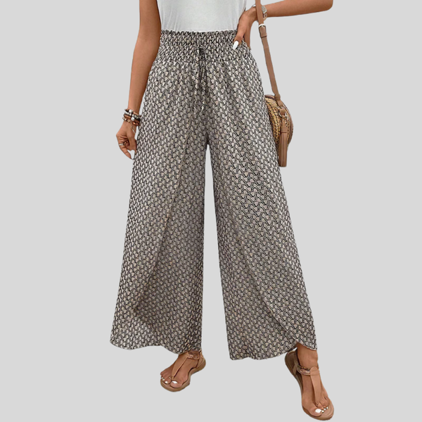 A woman wearing wide, flowing trousers in a beige-and-black geometric print with an elastic drawstring waist.