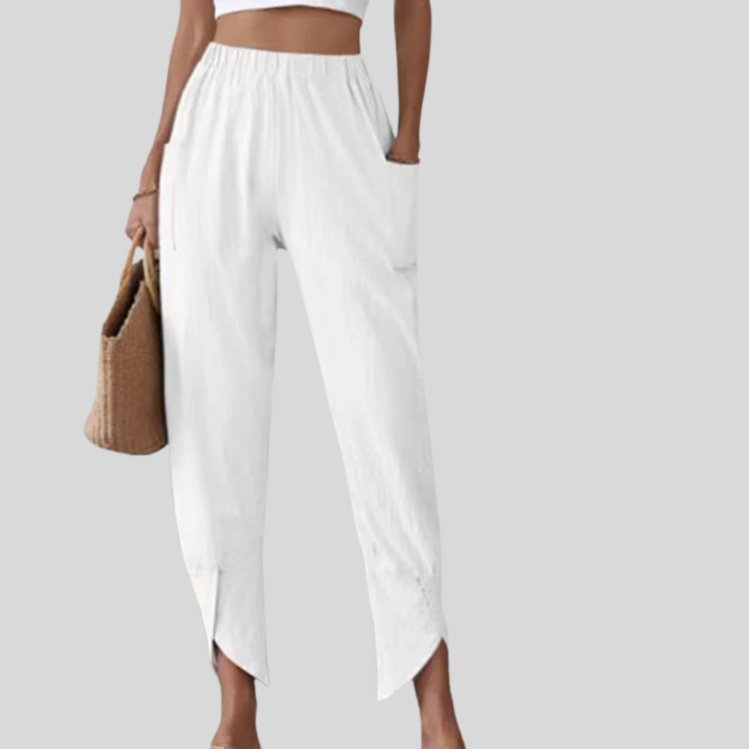 Woman wearing tapered trousers with a slit hem at the ankle, walking near the coast.