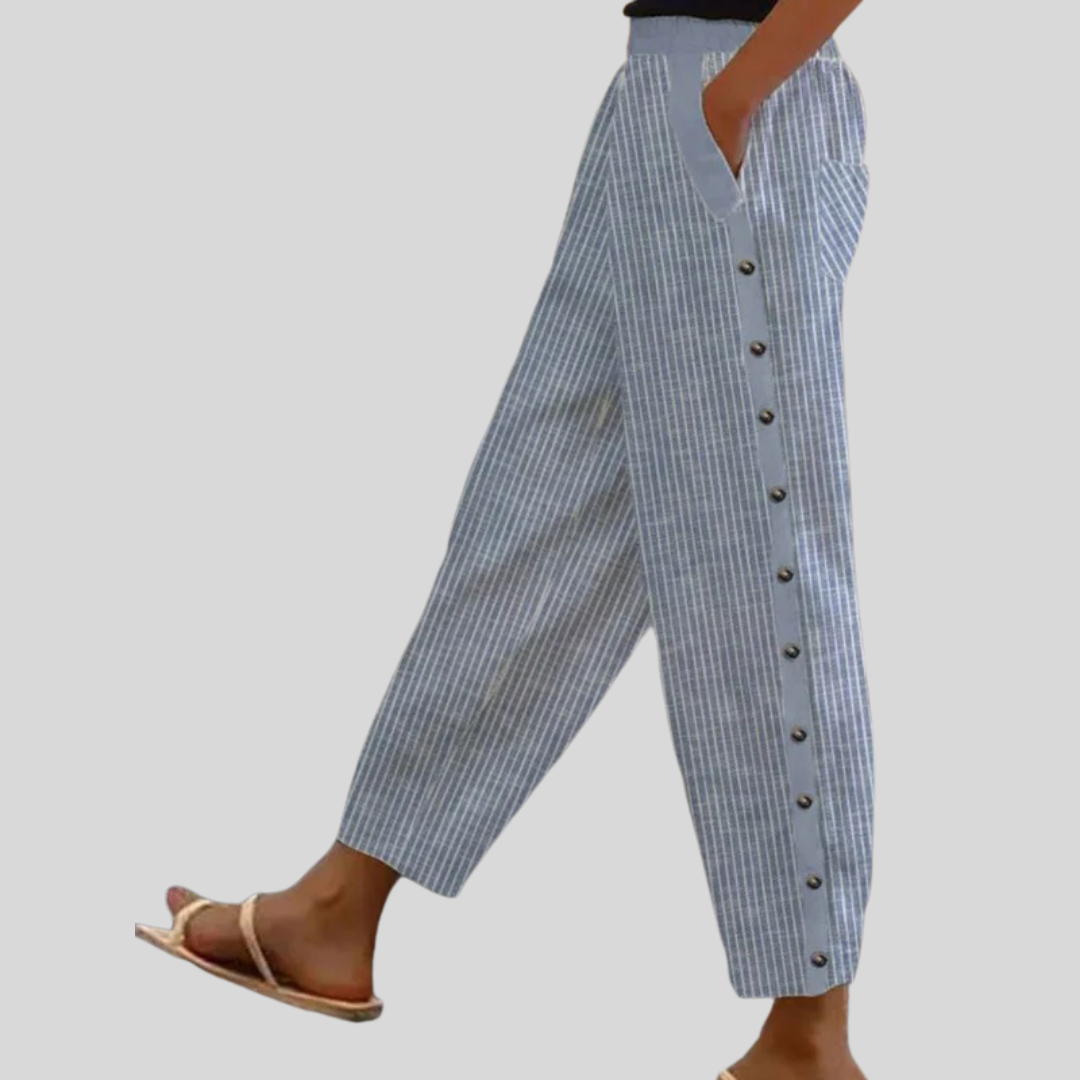 A woman wearing striped pull-on trousers with a side button detail and elastic waist.
