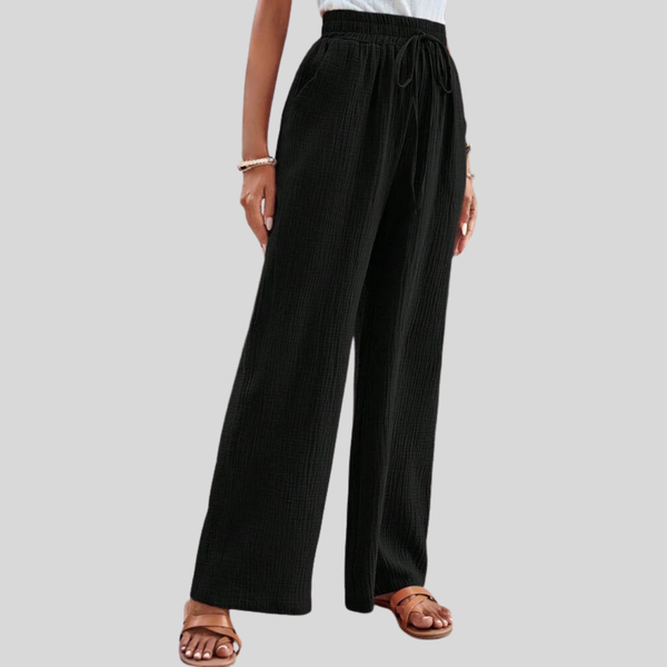 A woman in relaxed wide-leg trousers with a drawstring waist, styled for an easy casual look.