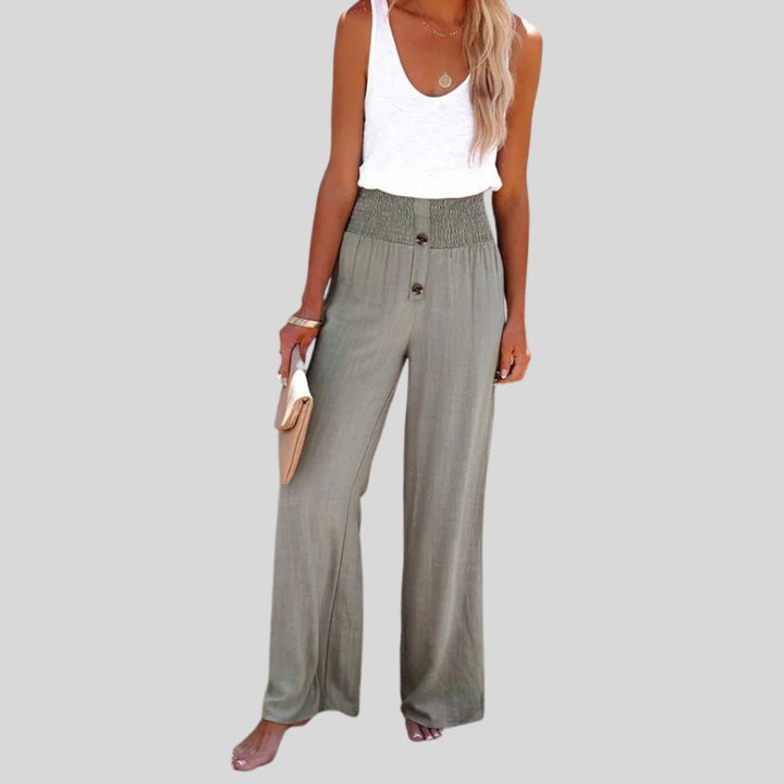 A woman in high-waisted loose wide-leg trousers with subtle button detailing, styled for an elegant everyday look.