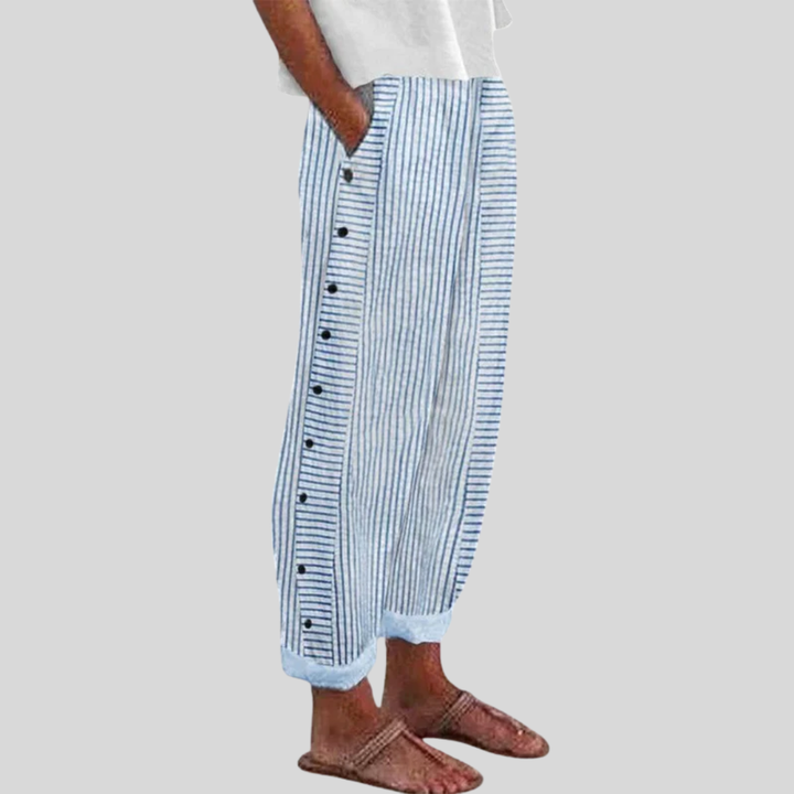 A woman wearing elegant everyday trousers in a fine blue stripe with a wide cut and side buttons.