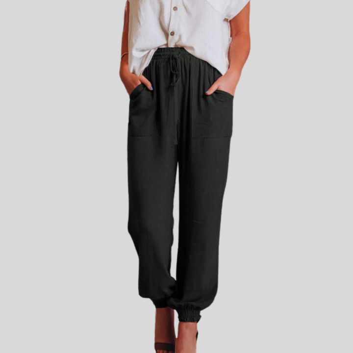 A woman in slim tapered drawstring joggers styled with sandals for an elegant, relaxed look.