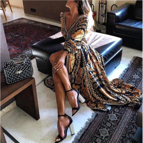 Woman at golden hour wearing the Tessa vintage print maxi dress with a waist belt and long statement sleeves.