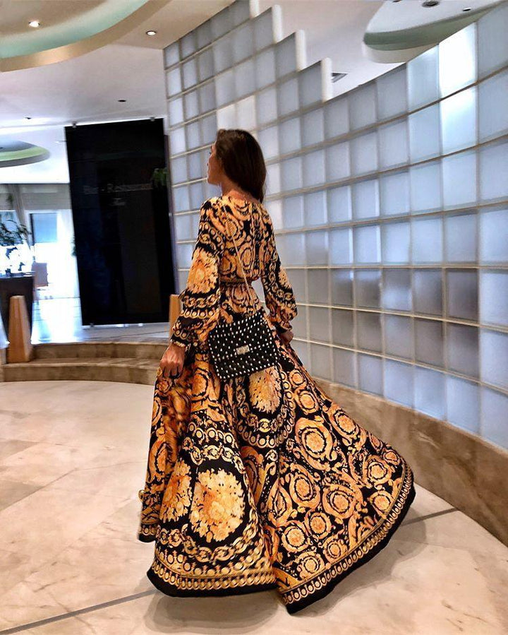 Woman at golden hour wearing the Tessa vintage print maxi dress with a waist belt and long statement sleeves.
