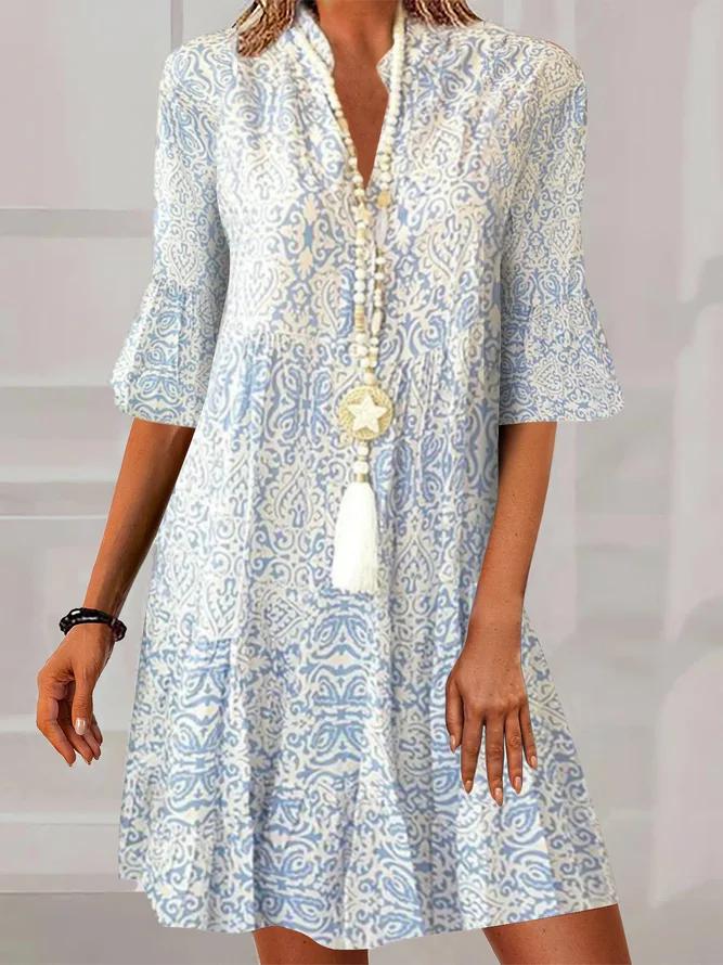 Woman wearing a flowing boho print dress with bell sleeves and a V-neckline.