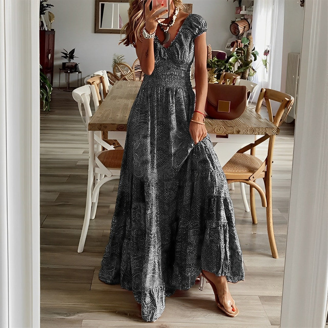 A woman wearing a patterned boho maxi dress with a gathered bodice and flowing layered skirt.