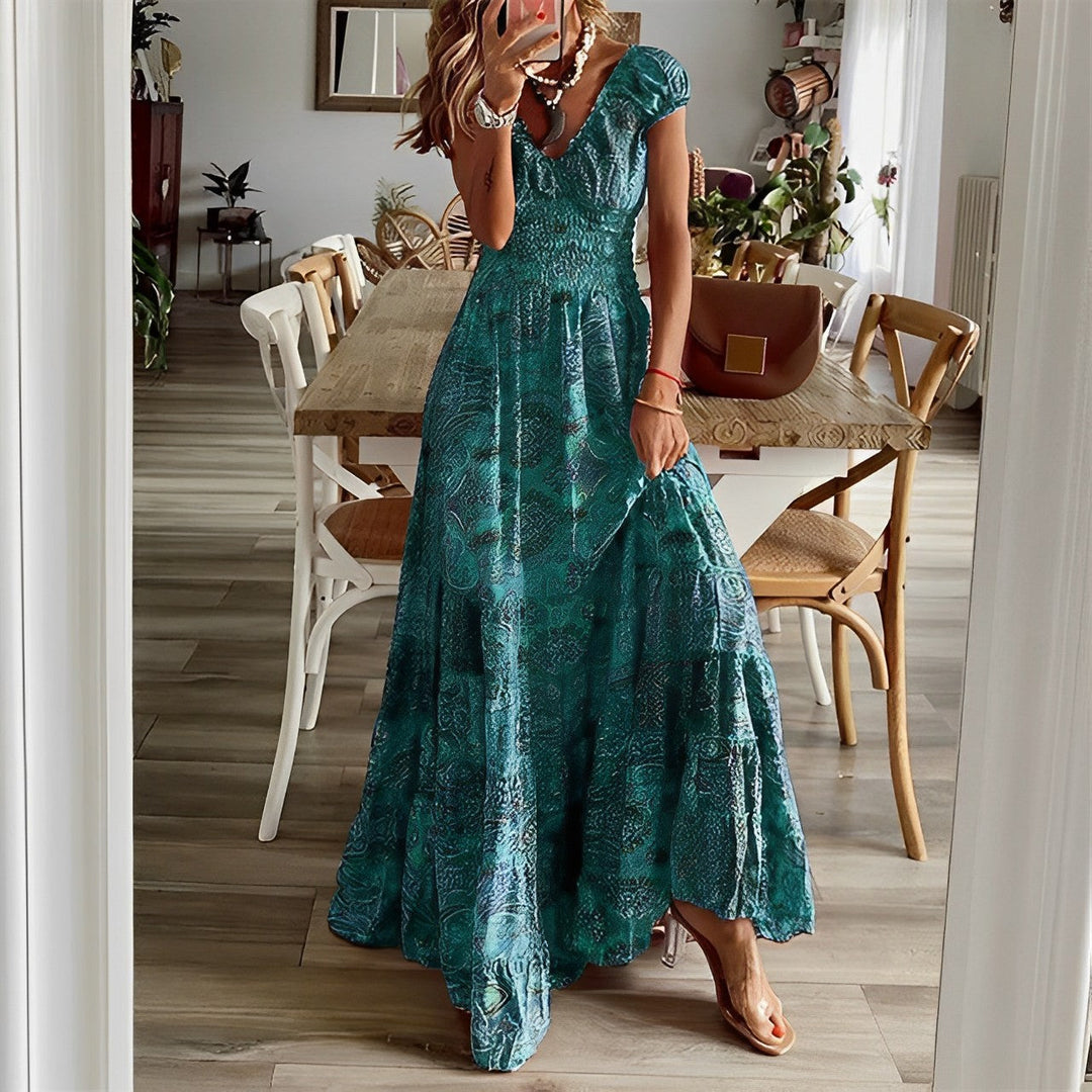 A woman wearing a patterned boho maxi dress with a gathered bodice and flowing layered skirt.