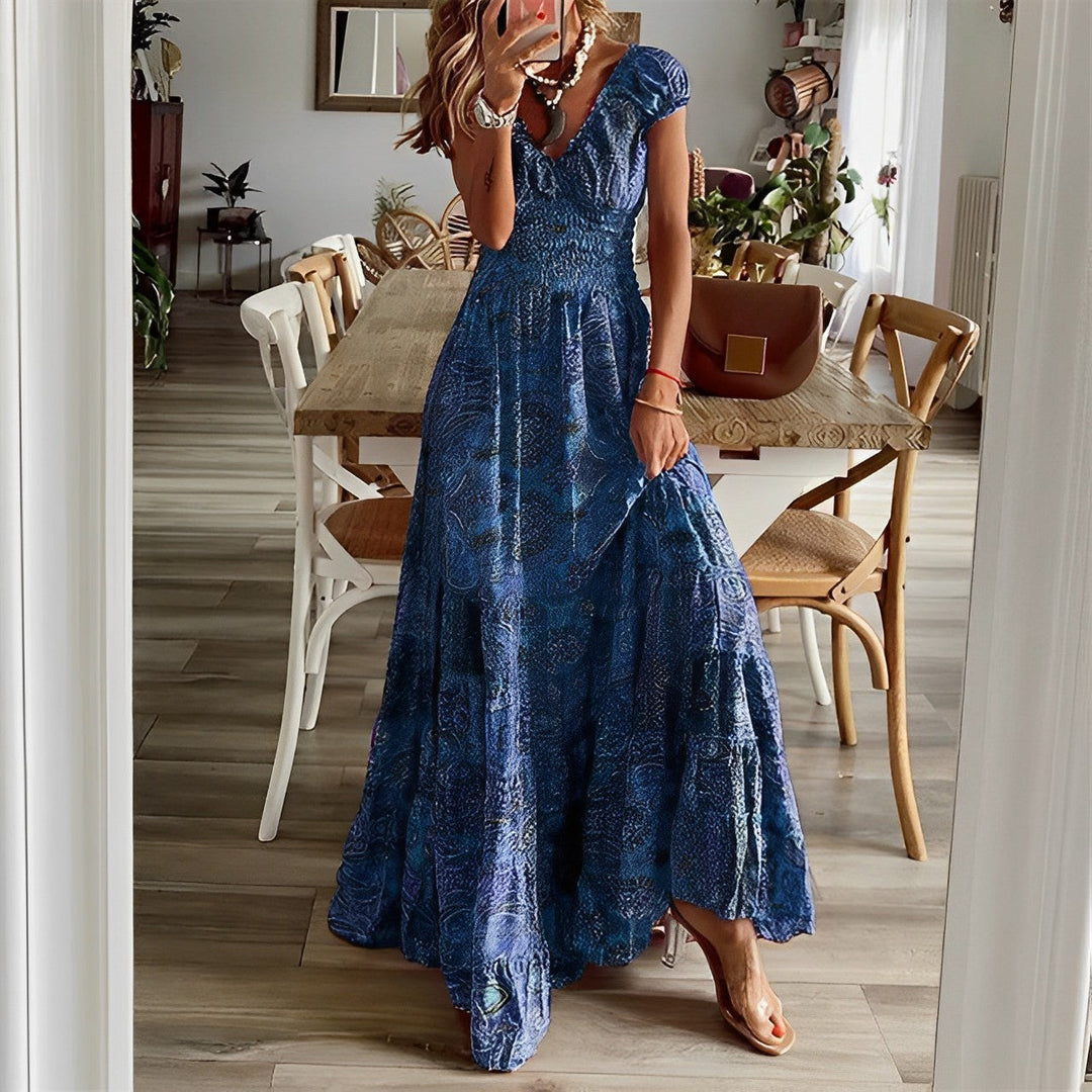 A woman wearing a patterned boho maxi dress with a gathered bodice and flowing layered skirt.