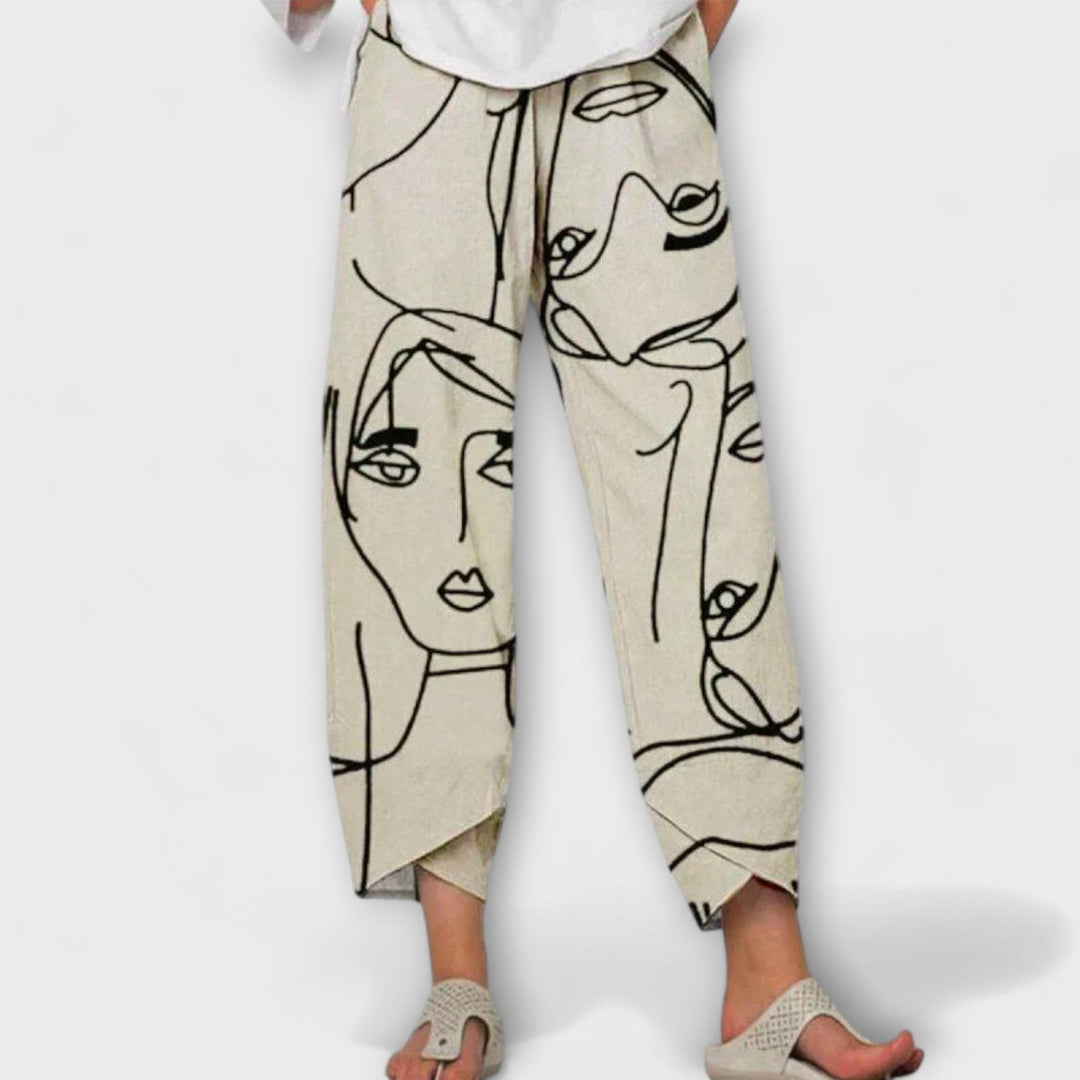 Woman wearing beige wide-leg trousers with an artistic face print and a simple top.