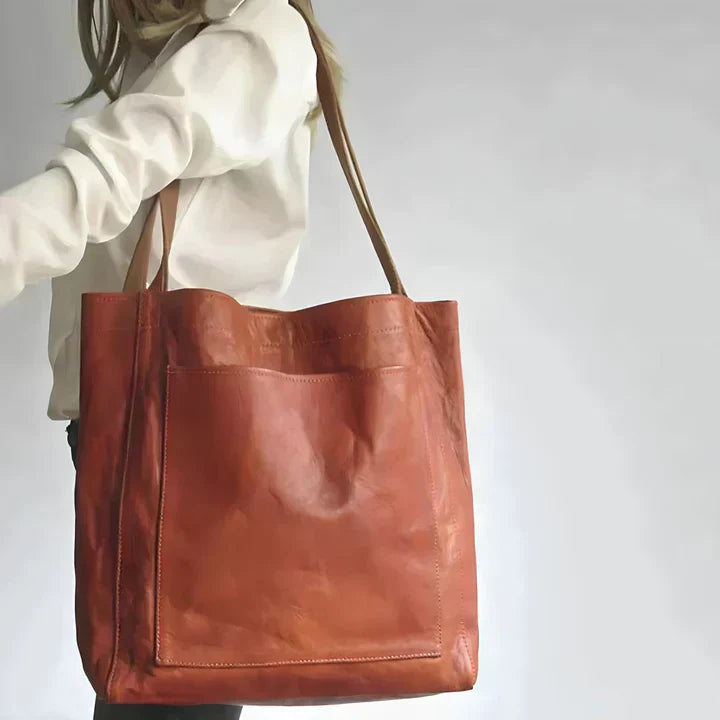 A woman holding a classic handbag with a rich finish by her side