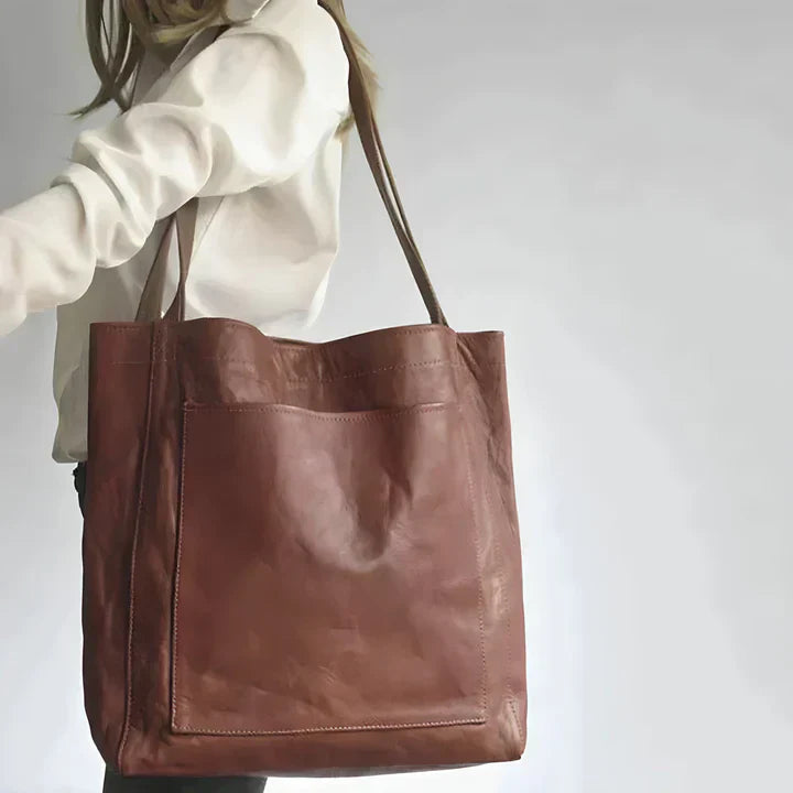 A woman holding a classic handbag with a rich finish by her side