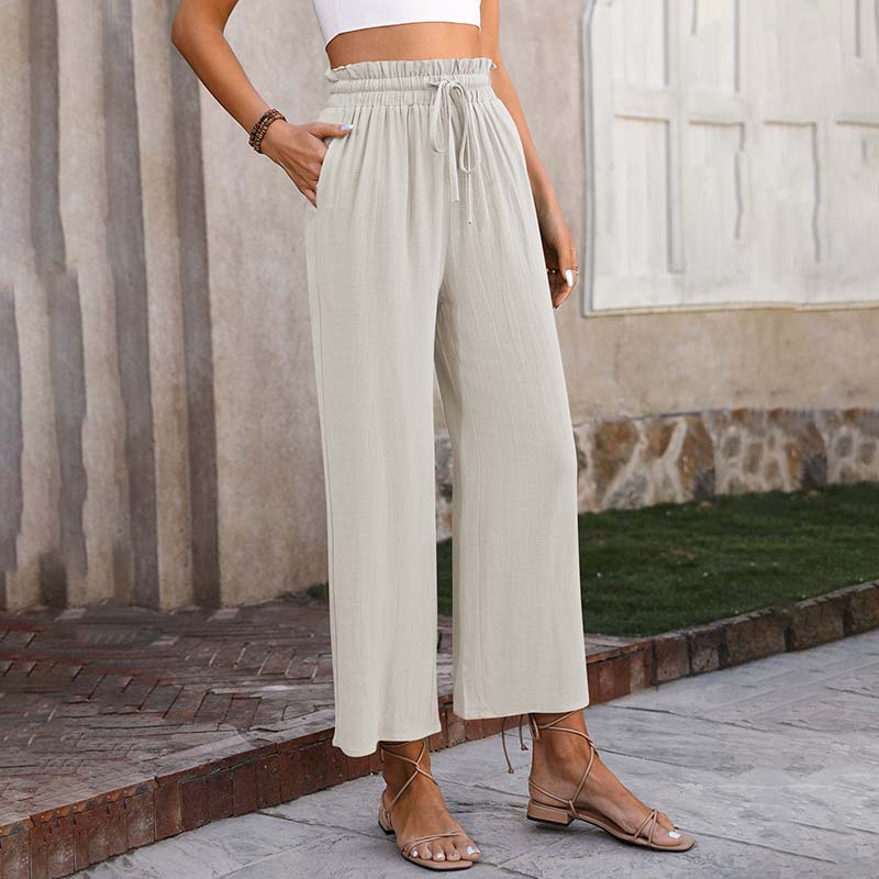 A woman in light cropped wide-leg trousers styled with sandals for a relaxed summer look.