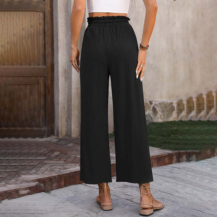 A woman in light cropped wide-leg trousers styled with sandals for a relaxed summer look.