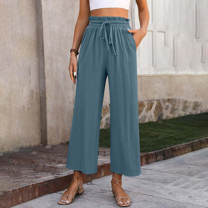 A woman in light cropped wide-leg trousers styled with sandals for a relaxed summer look.