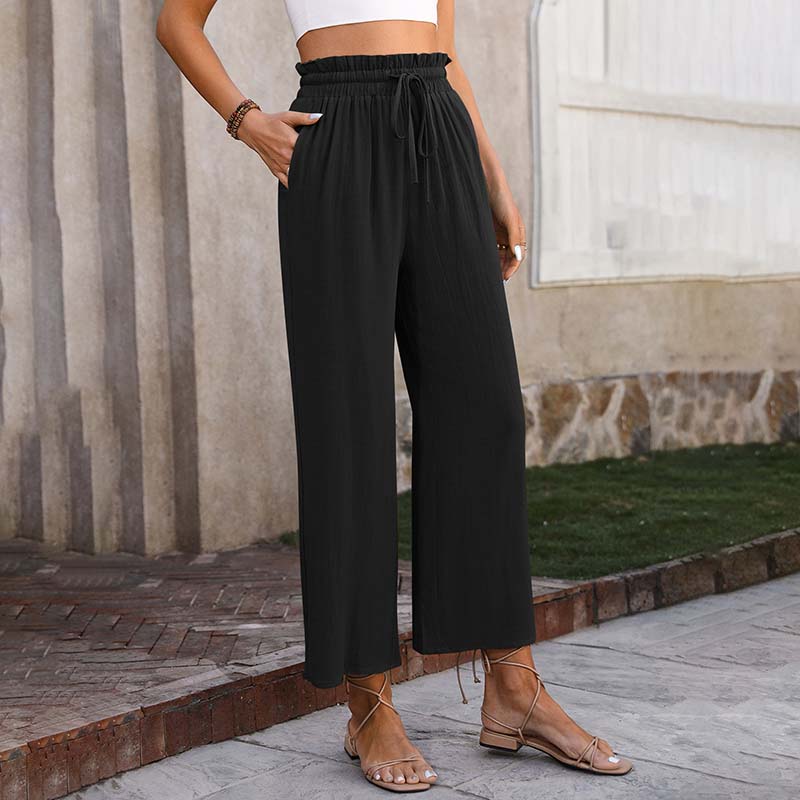 A woman in light cropped wide-leg trousers styled with sandals for a relaxed summer look.