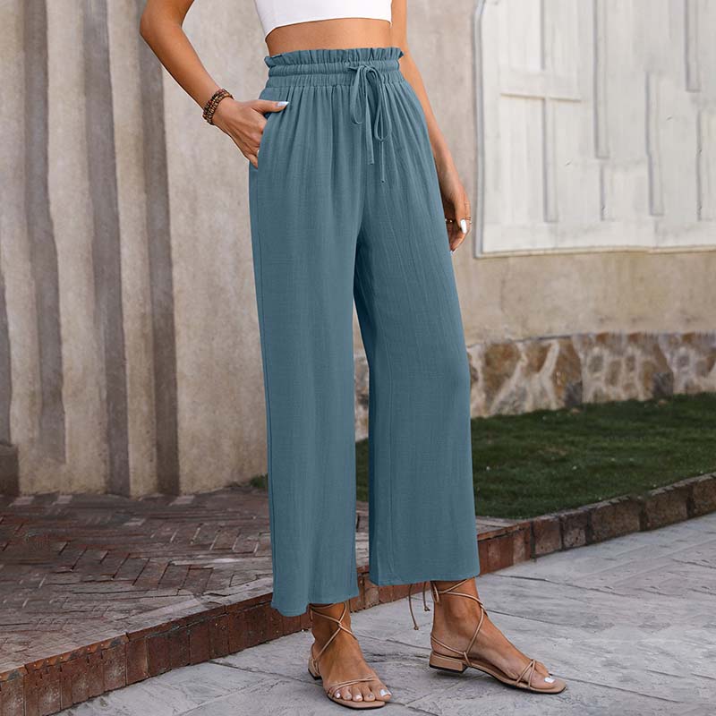 A woman in light cropped wide-leg trousers styled with sandals for a relaxed summer look.