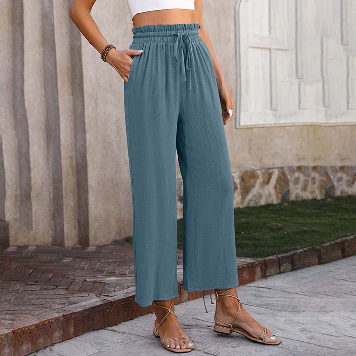 A woman in light cropped wide-leg trousers styled with sandals for a relaxed summer look.