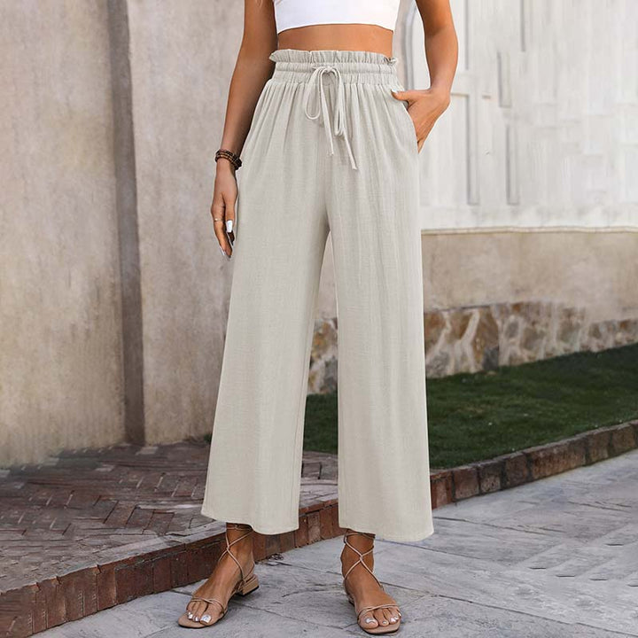 A woman in light cropped wide-leg trousers styled with sandals for a relaxed summer look.