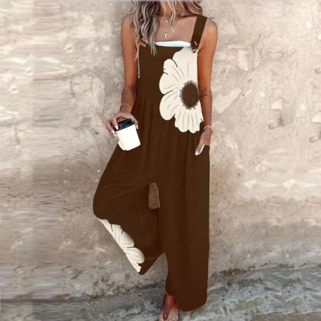 A woman wearing elegant black dungarees with a single large cream bloom and adjustable straps.