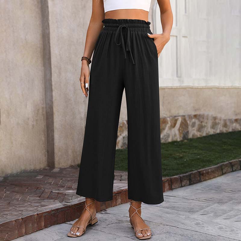 A woman in light cropped wide-leg trousers styled with sandals for a relaxed summer look.