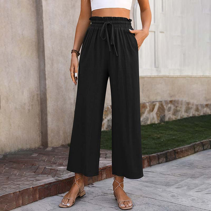 A woman in light cropped wide-leg trousers styled with sandals for a relaxed summer look.
