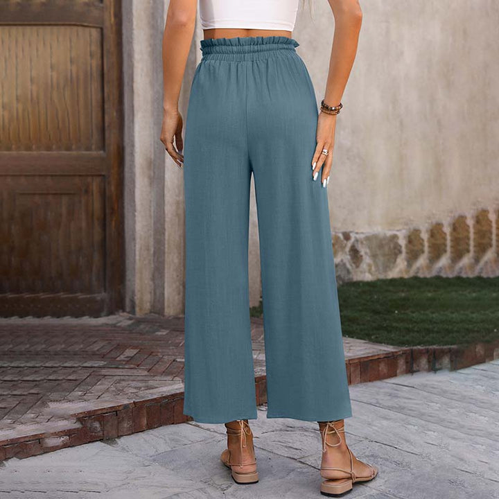 A woman in light cropped wide-leg trousers styled with sandals for a relaxed summer look.