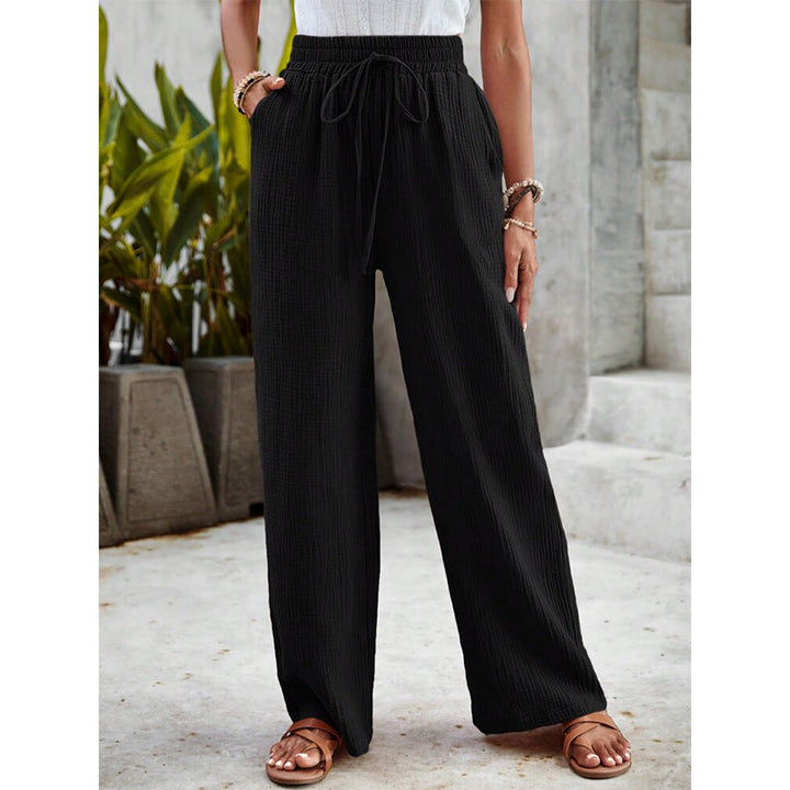 A woman in relaxed wide-leg trousers with a drawstring waist, styled for an easy casual look.