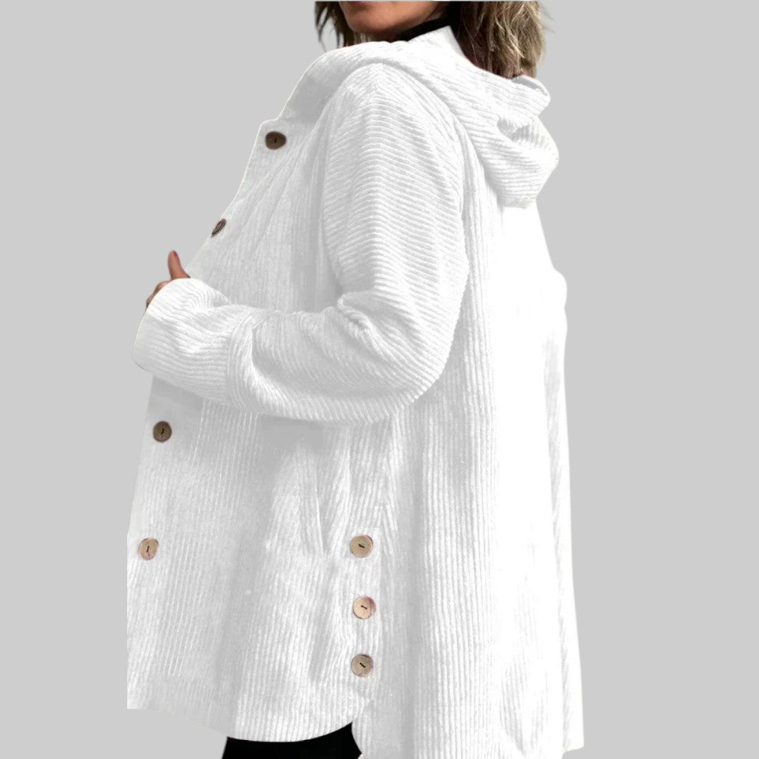 A woman wearing a hooded textured jacket outdoors in autumn