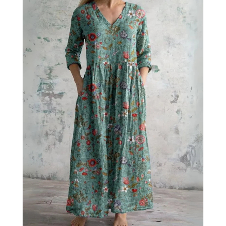A woman wearing the Assumpta vintage floral maxi dress with a gathered waist and flowing skirt at an outdoor celebration.