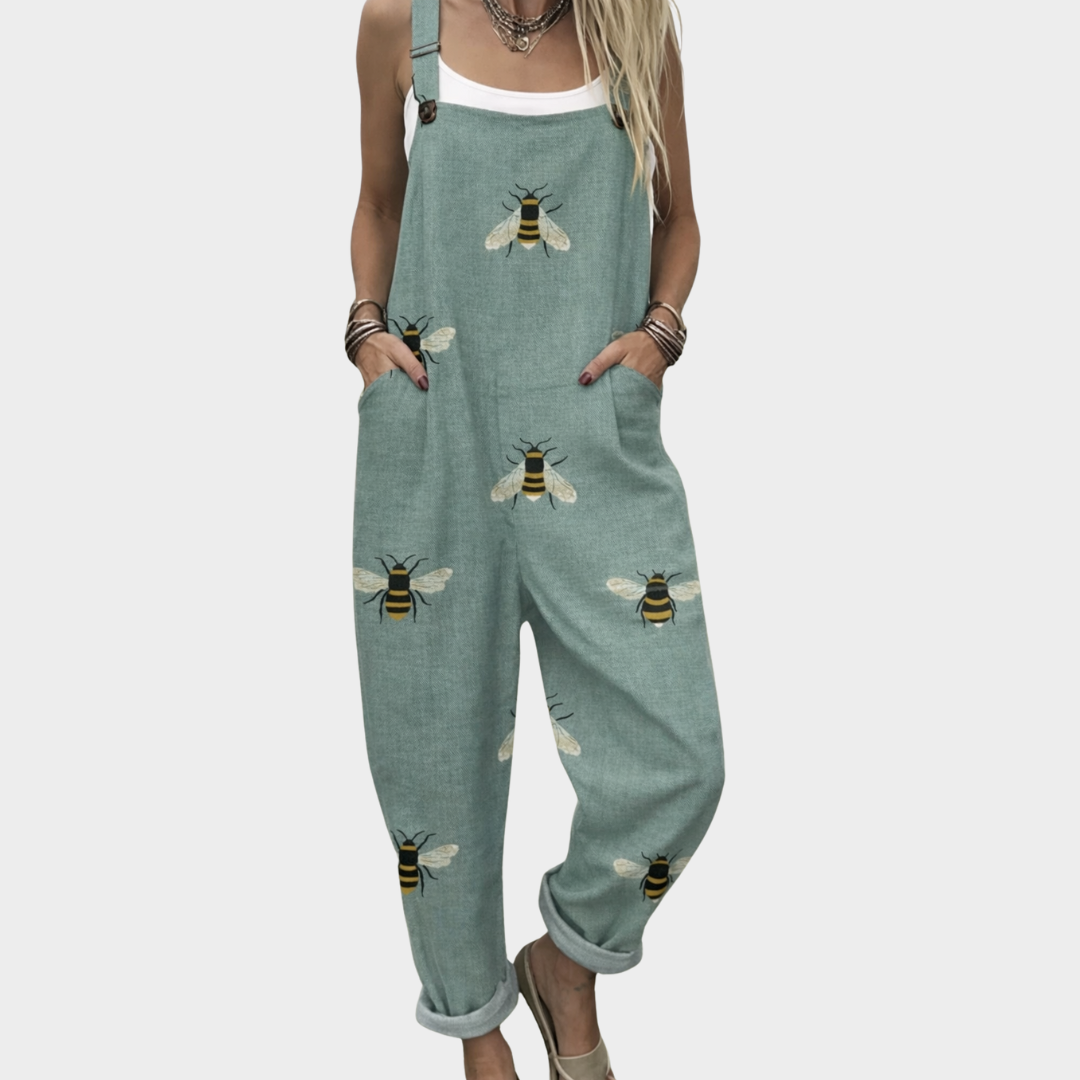 Woman wearing sage green dungarees with a scattered golden bee print, adjustable straps, cheerful and relaxed.